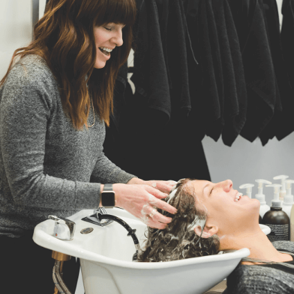 Female hairdresser washing customers hair